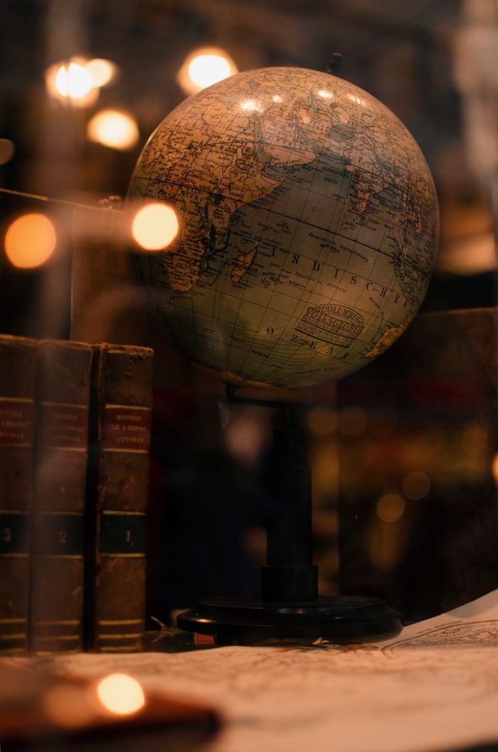 contact-img Through glass of world globe and ancient books placed behind transparent display in museum